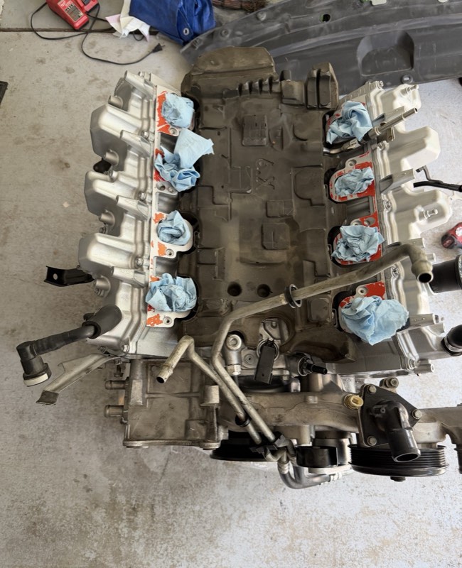 The top of an engine with shop towels covering the open intake ports.